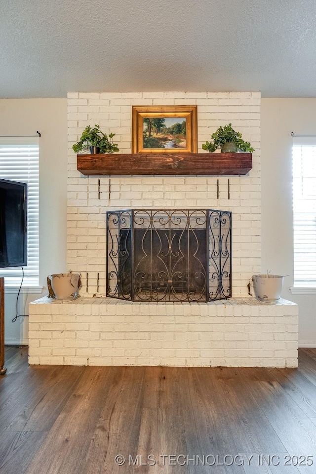 2520 Arlington Blvd, Ada, OK 74820 - detailed view of wood finished floors, a brick fireplace, and a textured ceiling