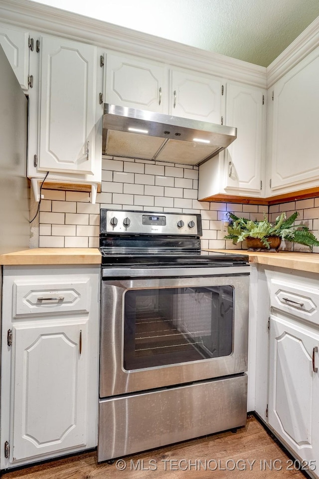 2520 Arlington Blvd, Ada, OK 74820 - kitchen with stainless steel range with electric cooktop, ventilation hood, butcher block countertops, white cabinetry, and decorative backsplash