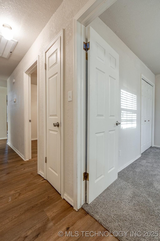 2520 Arlington Blvd, Ada, OK 74820 - hallway with wood finished floors, a textured ceiling, and a textured wall
