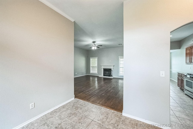 12003 S Tamarack St W, Jenks, OK 74037 - unfurnished living room featuring ceiling fan, light tile patterned floors, arched walkways, and a fireplace with raised hearth