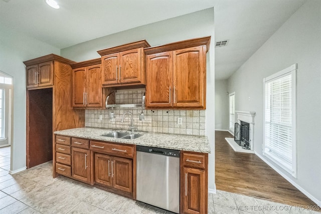 12003 S Tamarack St W, Jenks, OK 74037 - kitchen featuring stainless steel dishwasher, tasteful backsplash, light tile patterned flooring, light stone counters, and a fireplace with raised hearth