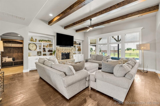6108 E 95th St, Sperry, OK 74073 - living area featuring a fireplace, ceiling fan, wood finished floors, arched walkways, and beamed ceiling