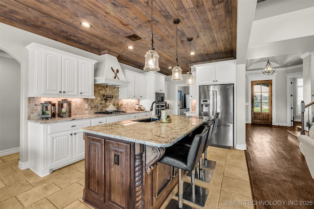 6108 E 95th St, Sperry, OK 74073 - kitchen featuring appliances with stainless steel finishes, wood ceiling, arched walkways, tasteful backsplash, and light stone countertops