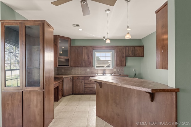 108 W 135th St, Skiatook, OK 74070 - kitchen with a kitchen bar, glass insert cabinets, tasteful backsplash, a peninsula, and light tile patterned flooring