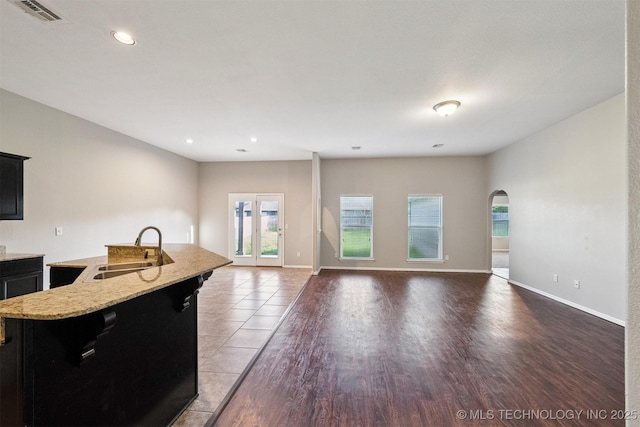 17409 E 44th St S, Tulsa, OK 74134 - kitchen with arched walkways, dark cabinetry, an island with sink, recessed lighting, and open floor plan