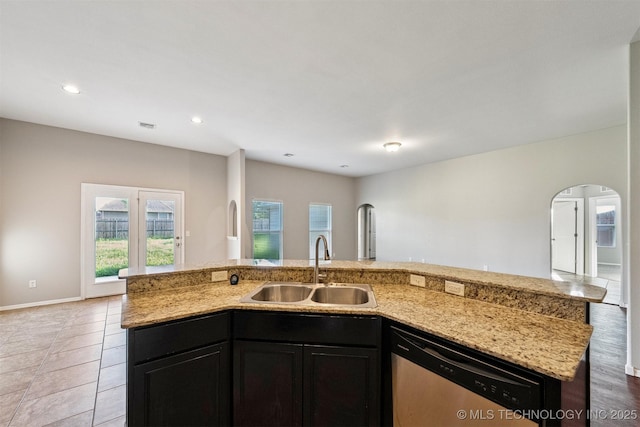 17409 E 44th St S, Tulsa, OK 74134 - kitchen featuring dishwasher, arched walkways, open floor plan, light stone counters, and a kitchen island with sink