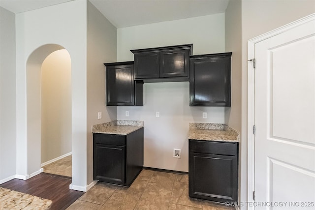 17409 E 44th St S, Tulsa, OK 74134 - kitchen with dark cabinetry, light stone countertops, and arched walkways