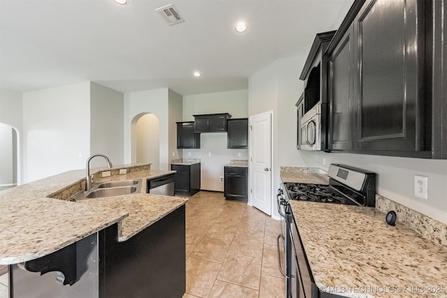 17409 E 44th St S, Tulsa, OK 74134 - kitchen featuring stainless steel appliances, arched walkways, dark cabinets, a spacious island, and recessed lighting