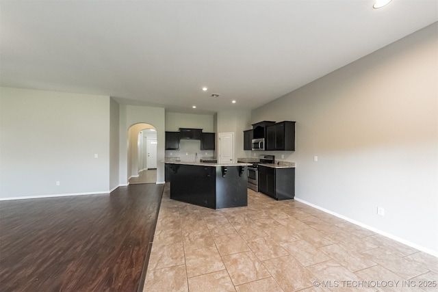 17409 E 44th St S, Tulsa, OK 74134 - kitchen with stainless steel appliances, dark cabinetry, arched walkways, light countertops, and open floor plan