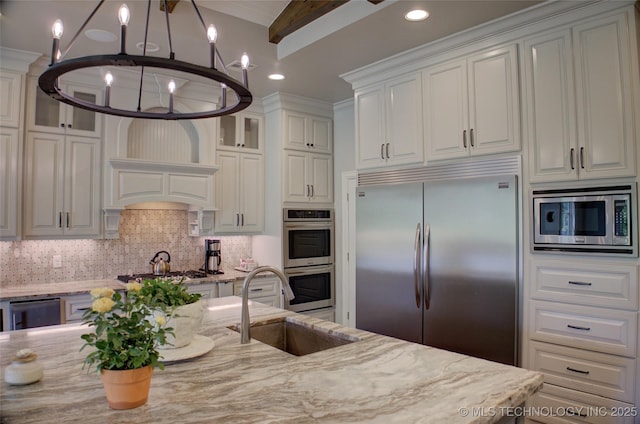 4401 S Yellow Pine Ave, Broken Arrow, OK 74011 - kitchen featuring built in appliances, a chandelier, light stone countertops, white cabinets, and glass insert cabinets