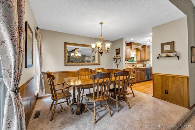 9601 Spring Lake Dr, Broken Arrow, OK 74014 - dining space with a wainscoted wall, a textured ceiling, wooden walls, a chandelier, and light colored carpet