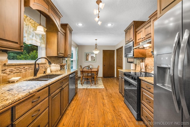 9601 Spring Lake Dr, Broken Arrow, OK 74014 - kitchen with appliances with stainless steel finishes, light wood-style floors, a textured ceiling, light stone countertops, and under cabinet range hood