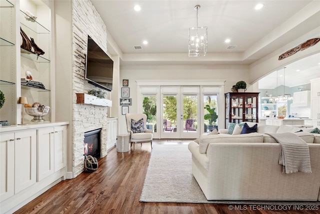 8701 E Hartford St, Broken Arrow, OK 74014 - living room featuring a stone fireplace, dark wood-style flooring, recessed lighting, a chandelier, and french doors