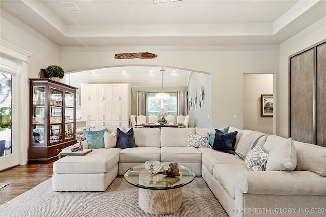 8701 E Hartford St, Broken Arrow, OK 74014 - living area with wood finished floors, a tray ceiling, and arched walkways