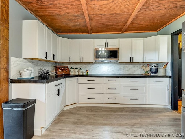 10696 N County Road 3410, Stratford, OK 74872 - kitchen with stainless steel microwave, a wood ceiling with exposed beams, white cabinets, backsplash, and dark countertops