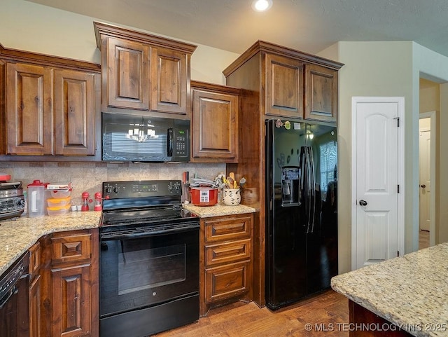 1125 Emily Ln, Ada, OK 74820 - kitchen featuring black appliances, backsplash, wood finished floors, and light stone countertops