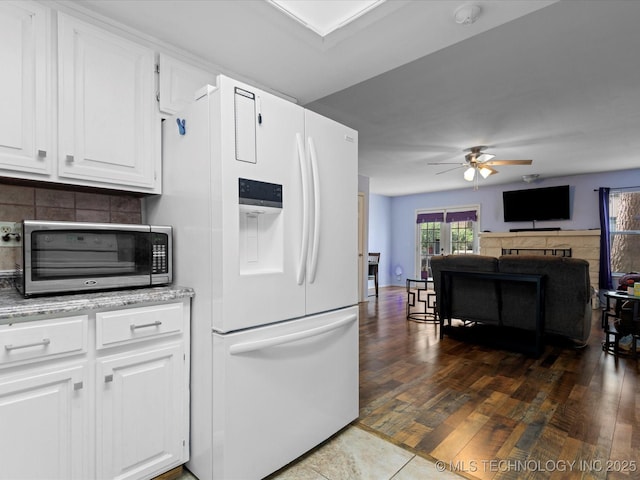 5229 Nowata Rd Unit F101, Bartlesville, OK 74006 - kitchen with white fridge with ice dispenser, ceiling fan, white cabinetry, stainless steel microwave, and backsplash