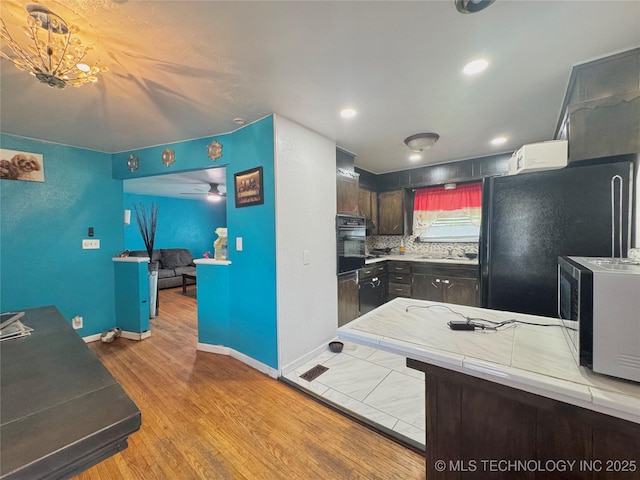 9763 E 3rd St, Tulsa, OK 74128 - kitchen with black appliances, wood finished floors, backsplash, recessed lighting, and a ceiling fan