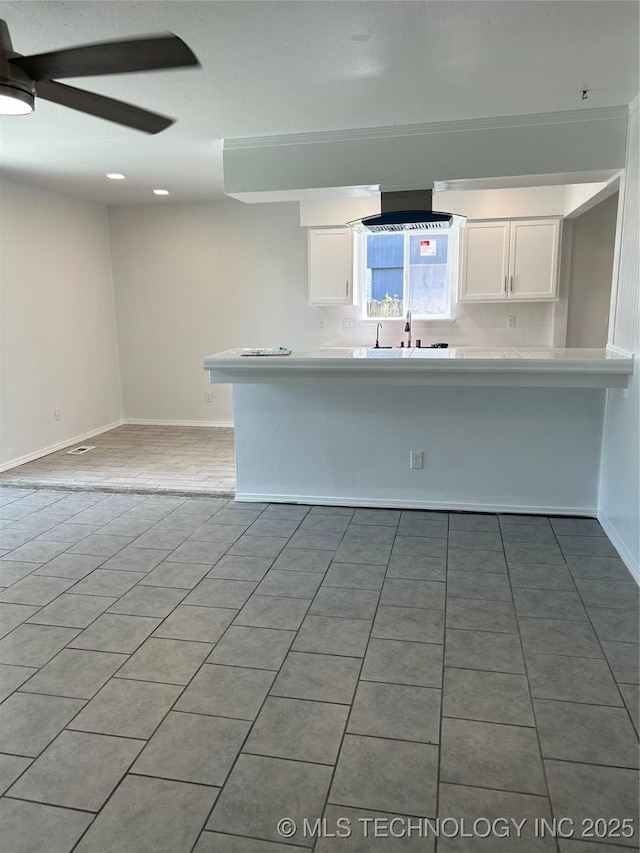 12976 E 32nd St, Tulsa, OK 74134 - kitchen with white cabinetry, ceiling fan, light countertops, a peninsula, and light tile patterned floors