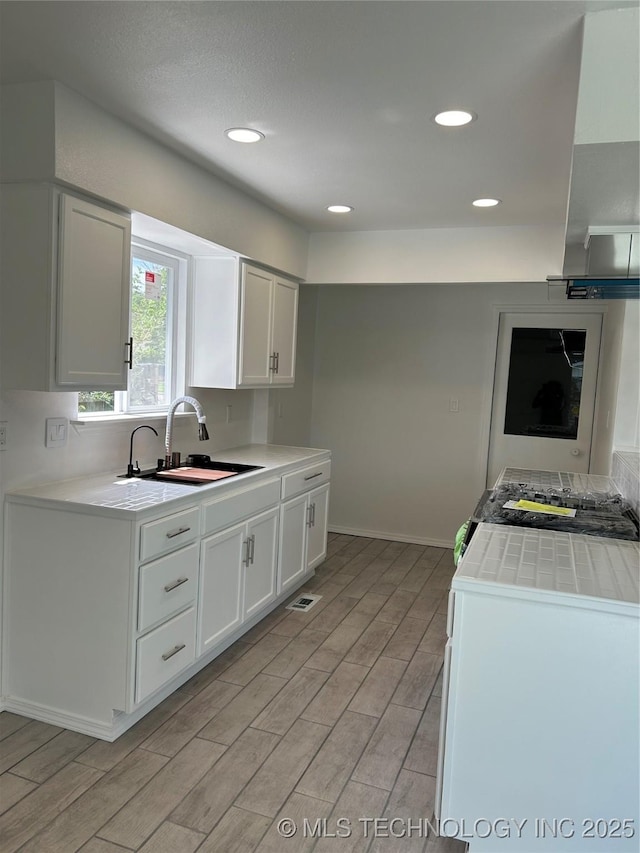12976 E 32nd St, Tulsa, OK 74134 - kitchen with light wood finished floors, white cabinetry, and recessed lighting