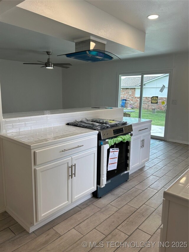 12976 E 32nd St, Tulsa, OK 74134 - kitchen featuring stainless steel range, wood finish floors, white cabinetry, light countertops, and recessed lighting