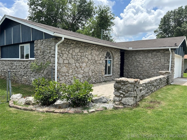 12976 E 32nd St, Tulsa, OK 74134 - view of side of property with stone siding, a lawn, and a garage