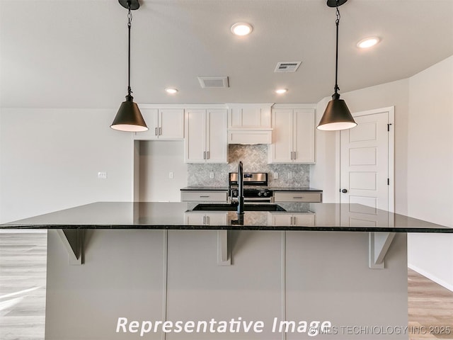 7218 E 132nd St S, Bixby, OK 74008 - kitchen featuring white cabinetry, light wood-style flooring, a kitchen breakfast bar, backsplash, and recessed lighting