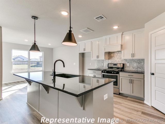 7218 E 132nd St S, Bixby, OK 74008 - kitchen featuring stainless steel range with gas stovetop, backsplash, custom range hood, light wood-type flooring, and a kitchen bar