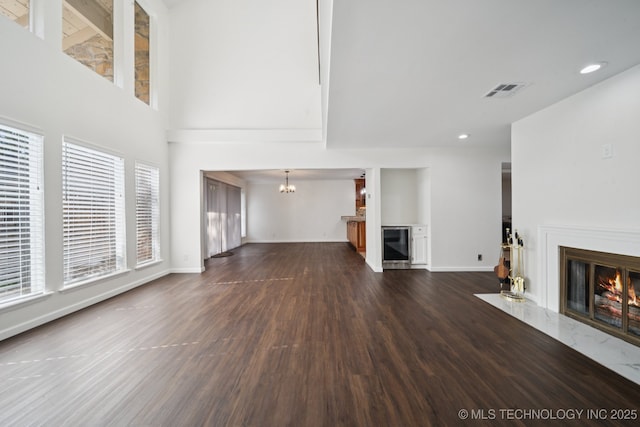 6002 S Atlanta Ct Unit 2, Tulsa, OK 74105 - unfurnished living room featuring a high end fireplace, a chandelier, dark wood finished floors, recessed lighting, and wine cooler