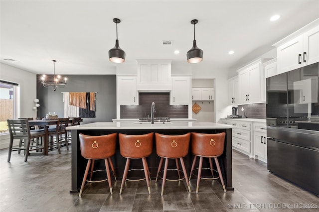 2035 E 138th Pl S, Bixby, OK 74008 - kitchen with freestanding refrigerator, backsplash, a center island with sink, light countertops, and recessed lighting