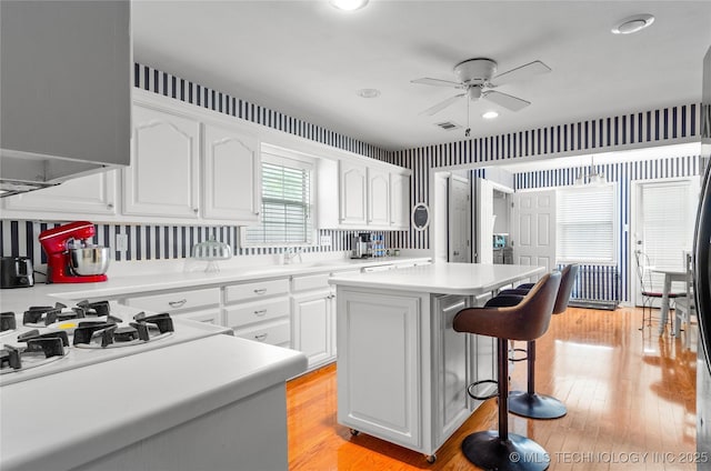 925 W Cedar St N, Durant, OK 74701 - kitchen featuring a kitchen bar, ceiling fan, a center island, white cabinetry, and light countertops