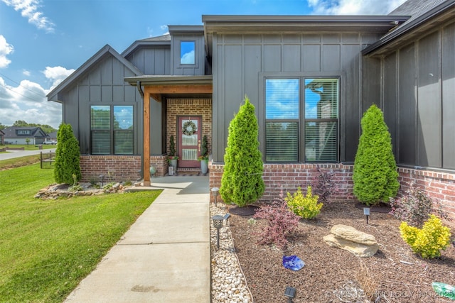 2407 W Union Pl, Collinsville, OK 74021 - doorway to property featuring board and batten siding, brick siding, and a lawn