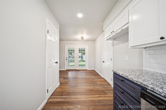 16524 E 2nd St, Tulsa, OK 74108 - kitchen featuring stainless steel dishwasher, dark wood-type flooring, white cabinets, backsplash, and a textured ceiling