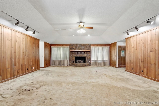 2425 E 53rd St, Tulsa, OK 74105 - unfurnished living room featuring rail lighting, vaulted ceiling, wood walls, ceiling fan, and a textured ceiling