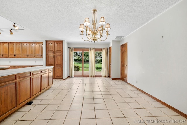 2425 E 53rd St, Tulsa, OK 74105 - kitchen with a textured ceiling, light countertops, a chandelier, brown cabinets, and decorative light fixtures