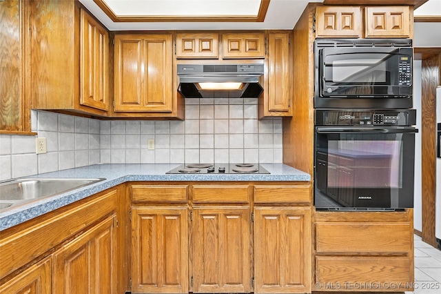 32069 Meadow Ln, Mannford, OK 74044 - kitchen featuring black appliances, under cabinet range hood, brown cabinets, light tile patterned floors, and decorative backsplash
