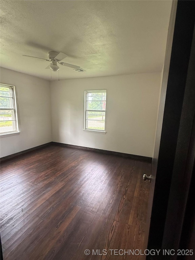426 S 12th, Durant, OK 74701 - unfurnished room with dark wood-style flooring, healthy amount of natural light, a textured ceiling, and a ceiling fan