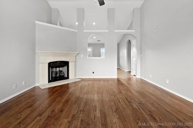 40 E Fairlane Pl, Sapulpa, OK 74066 - unfurnished living room featuring a fireplace with raised hearth, wood finished floors, ceiling fan, high vaulted ceiling, and arched walkways