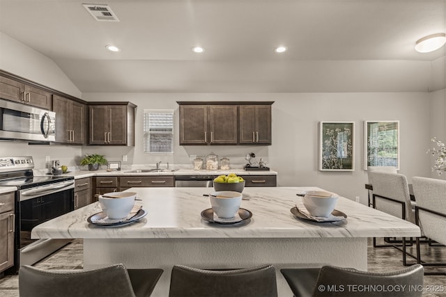 7420 E 160th Pl S, Bixby, OK 74008 - kitchen featuring stainless steel appliances, vaulted ceiling, a kitchen breakfast bar, dark brown cabinetry, and light stone countertops