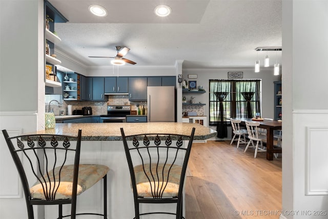 1934 Birnamwood, Miami, OK 74354 - kitchen with open shelves, stainless steel appliances, blue cabinetry, ceiling fan, and a textured ceiling