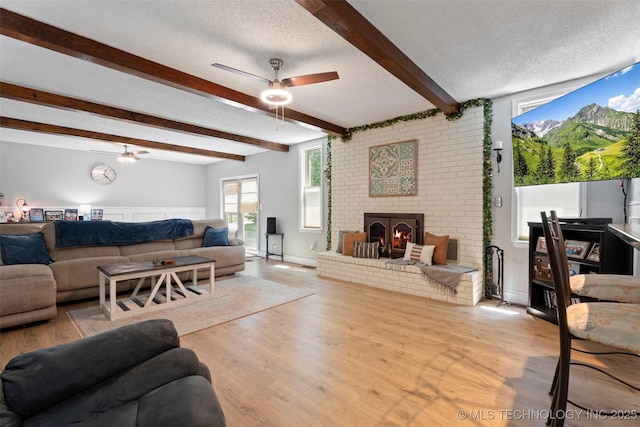 1934 Birnamwood, Miami, OK 74354 - living room with a ceiling fan, a textured ceiling, wood finished floors, beam ceiling, and a brick fireplace