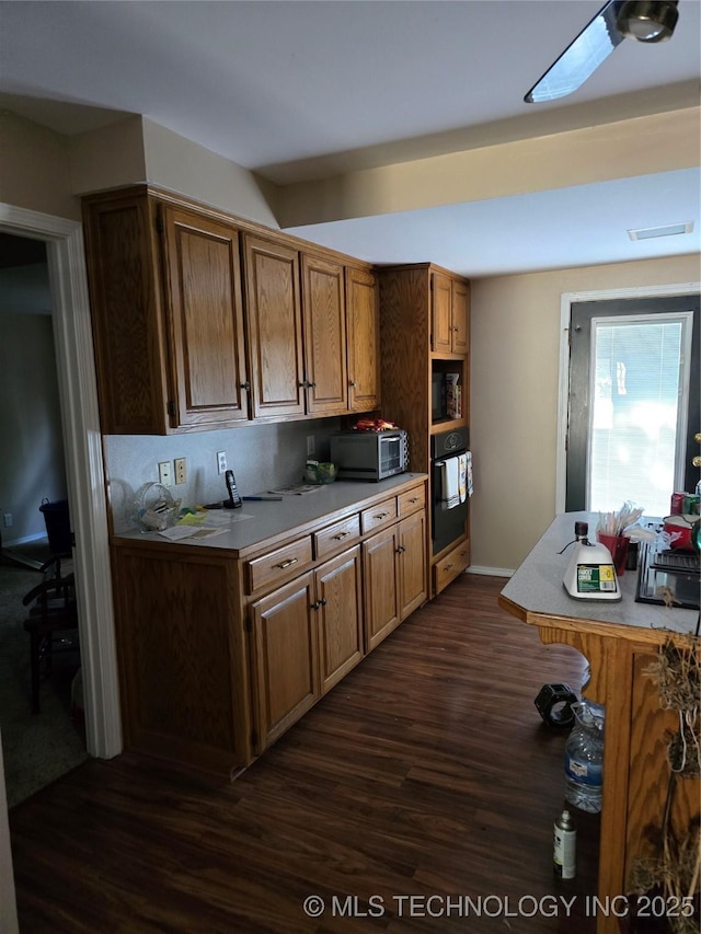 617 N 11th St, Pawnee, OK 74058 - kitchen featuring black oven, dark wood-type flooring, stainless steel microwave, brown cabinetry, and ceiling fan