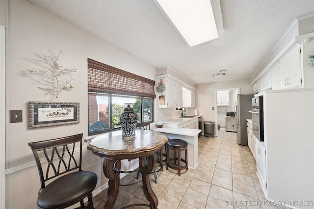 7058 E 52nd Pl, Tulsa, OK 74145 - kitchen with a peninsula, stainless steel appliances, light countertops, white cabinetry, and light tile patterned floors