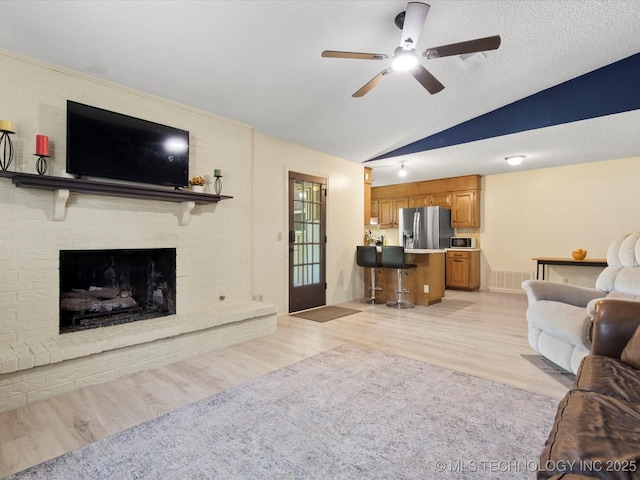 1267 Guinn Ln, Bartlesville, OK 74006 - living room with vaulted ceiling, a ceiling fan, light wood-style floors, and a fireplace