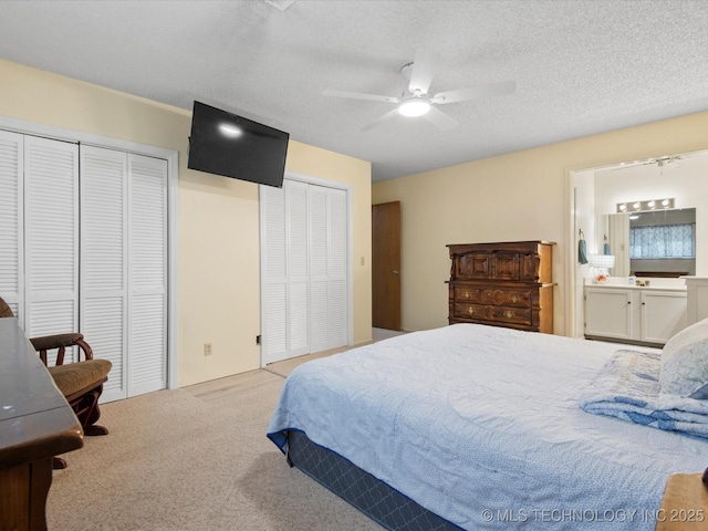 1267 Guinn Ln, Bartlesville, OK 74006 - carpeted bedroom featuring two closets, a ceiling fan, connected bathroom, and a textured ceiling