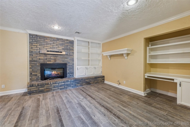3609 E Scenic Dr, Cushing, OK 74023 - unfurnished living room with a textured ceiling, built in shelves, built in desk, wood finished floors, and a fireplace