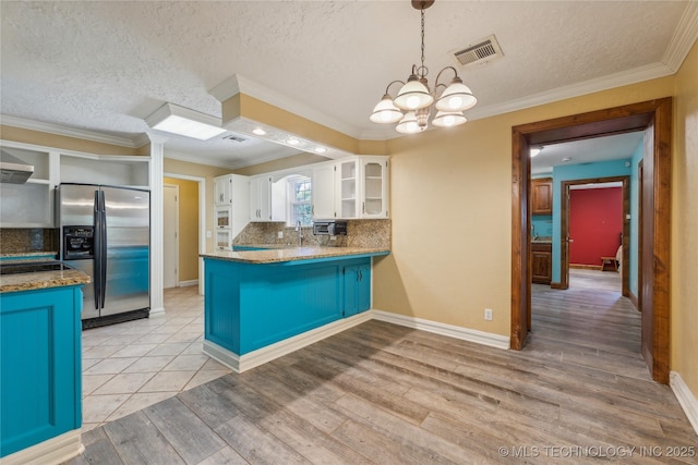 3609 E Scenic Dr, Cushing, OK 74023 - kitchen with stainless steel fridge, open shelves, a peninsula, white cabinetry, and a chandelier