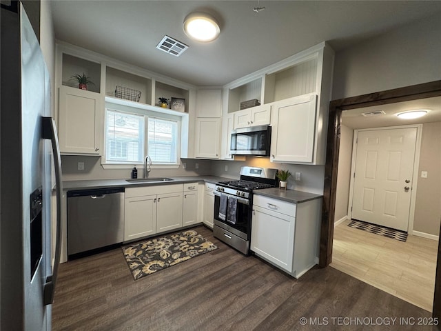 911 E Maple St, Cushing, OK 74023 - kitchen with stainless steel appliances, dark wood-style floors, white cabinetry, and dark countertops