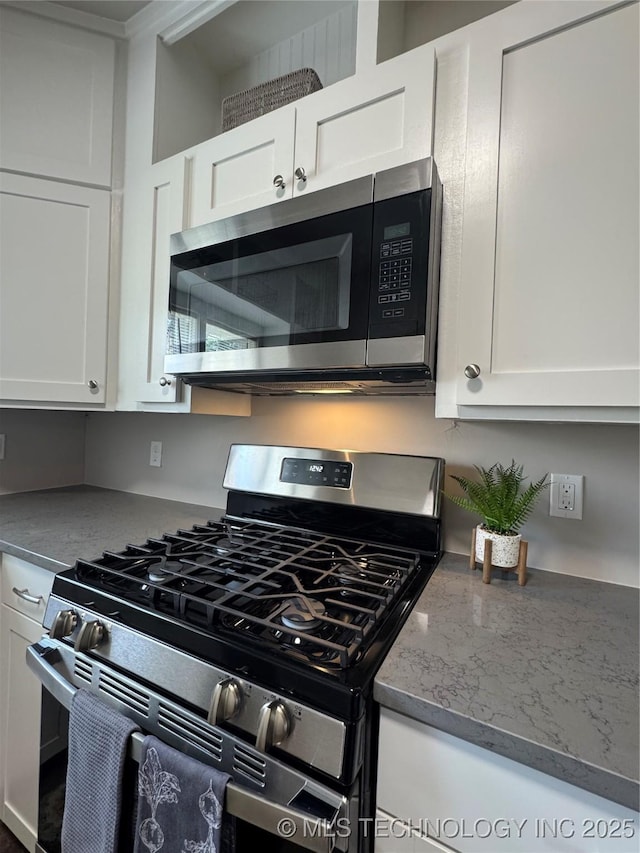 911 E Maple St, Cushing, OK 74023 - kitchen featuring appliances with stainless steel finishes, white cabinetry, and light stone counters
