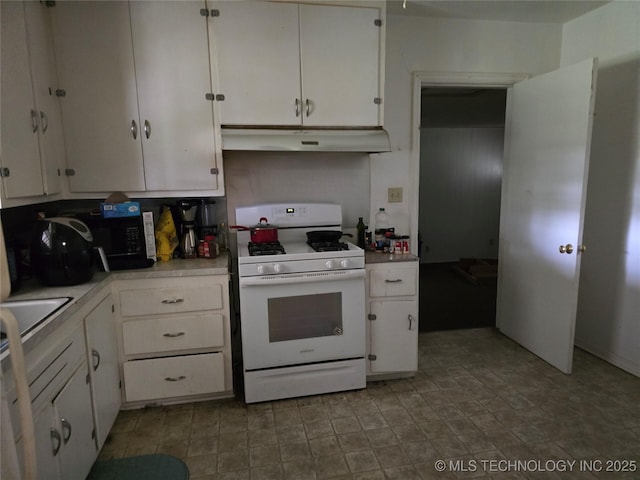 615 11th St, Pawnee, OK 74058 - kitchen featuring white gas range oven, under cabinet range hood, white cabinetry, and light countertops
